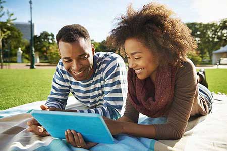 Man and woman at the park looking at a tablet