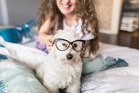kid putting glasses on her dog